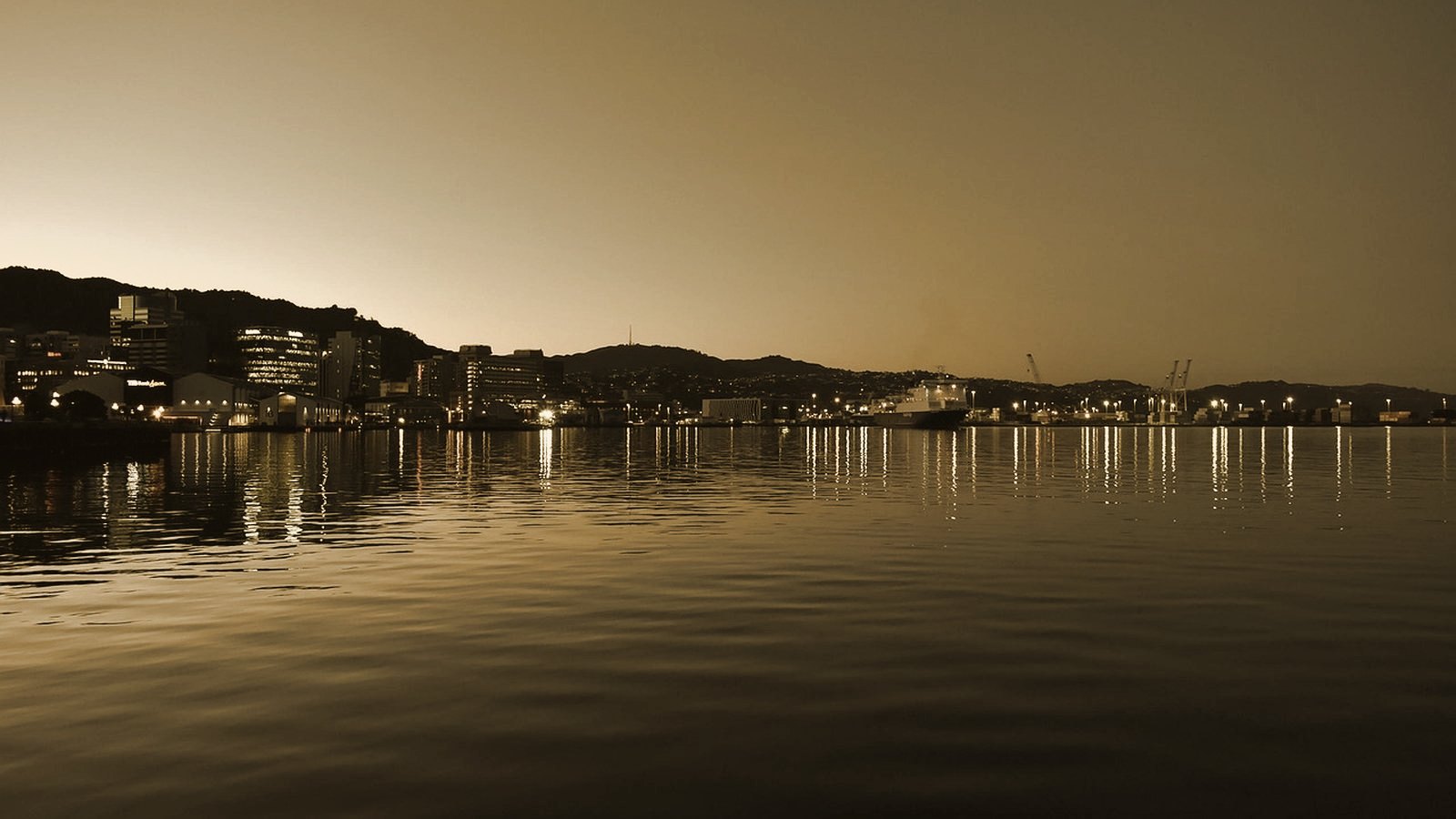 Wellington harbour at dusk with city lights reflected on the water