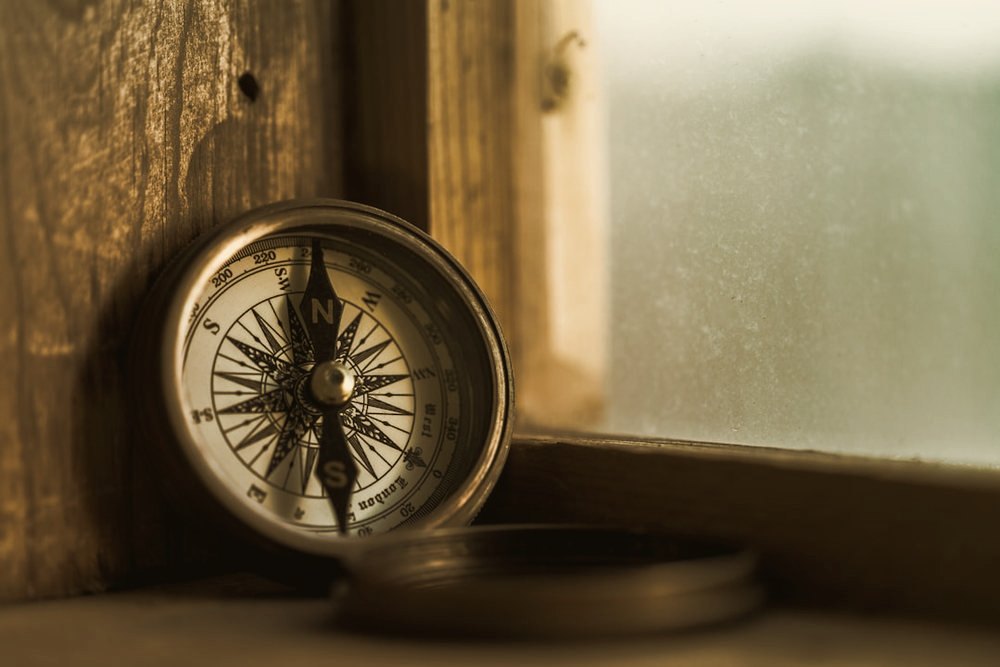 A brass compass resting on a wooden window sill